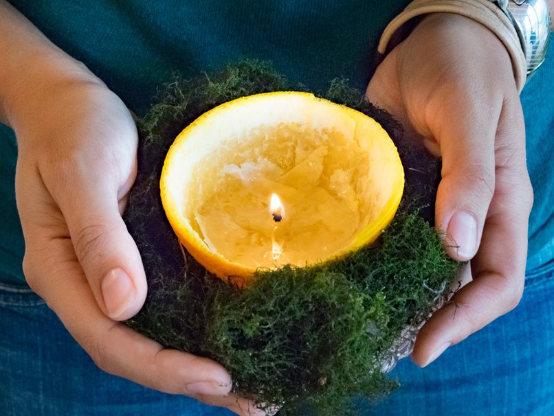 In den Händen gehaltene Orangenkerze