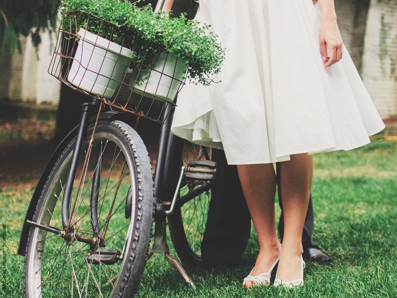 Braut neben dekoriertem Fahrrad